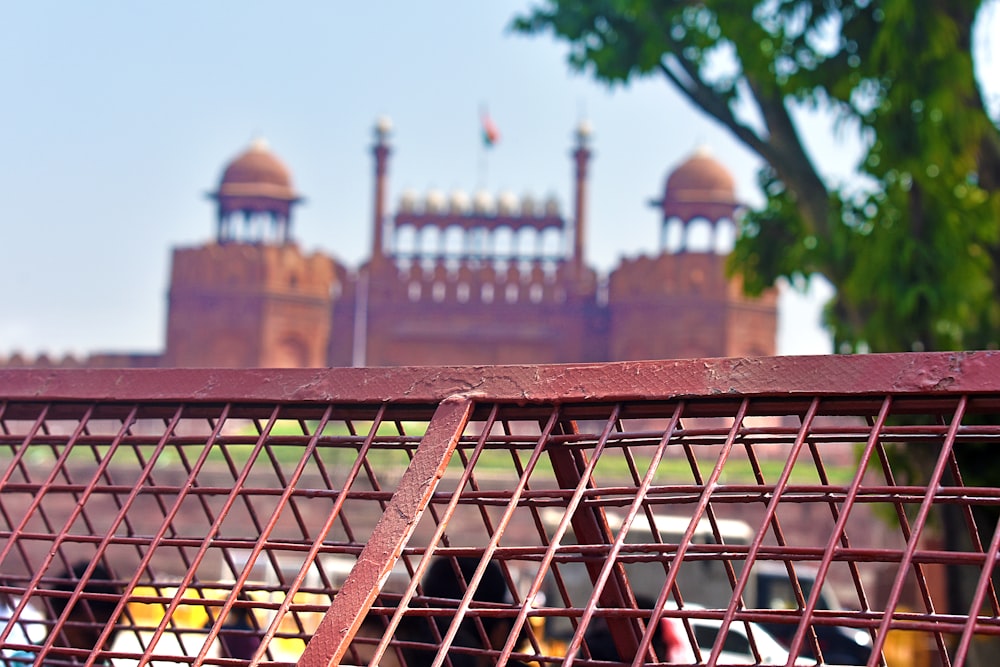 a red metal fence with a building in the background