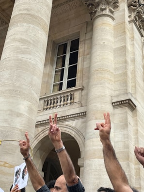 A group of diverse people holding hands in front of a historic courthouse.