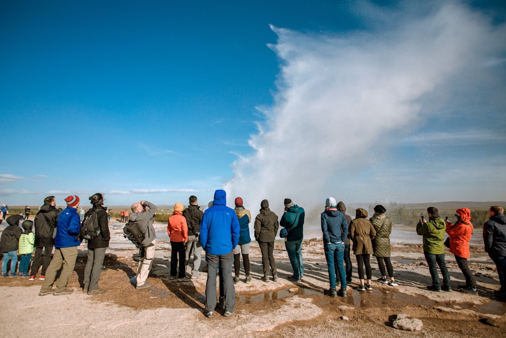 a group of people standing on a rocky hill with a cloud of smoke