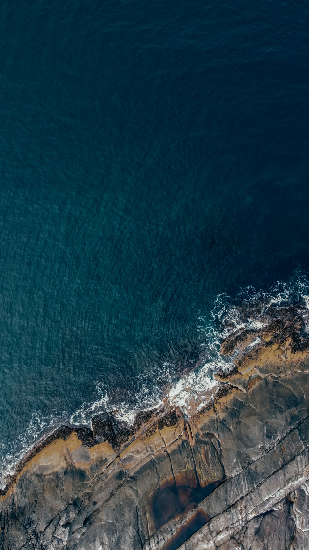 a rocky cliff with a body of water in the background