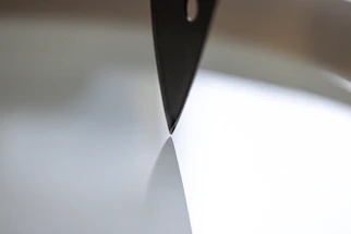 A close-up of a sleek medical scalpel resting on a crisp parchment background.