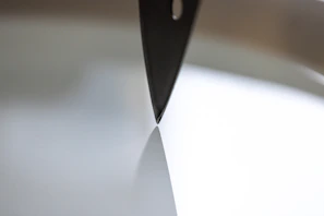 Black and white photo of a man sharpening a blade, symbolizing discipline and preparation.