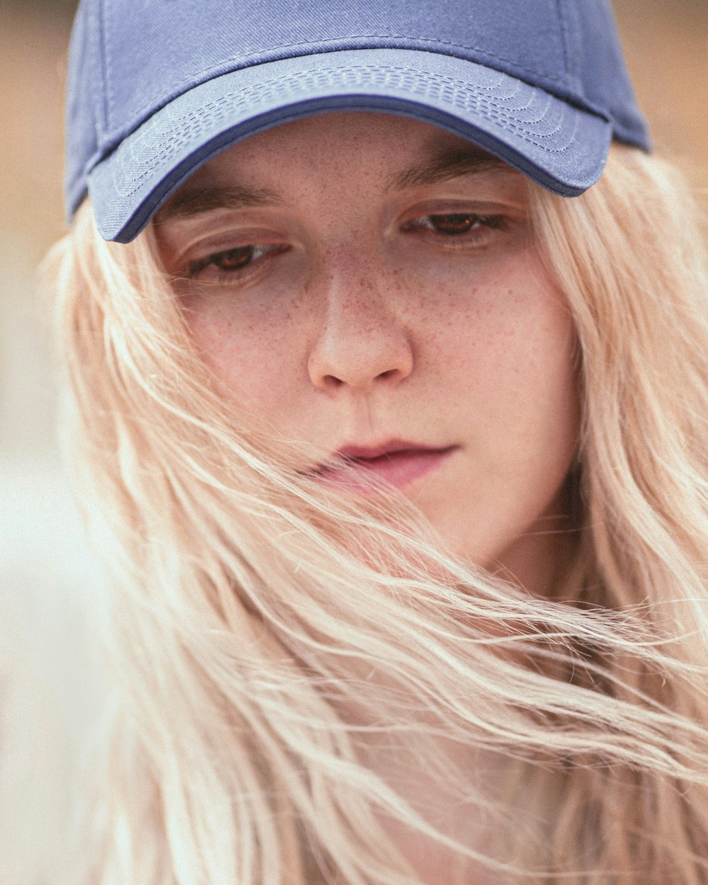 a woman with long blonde hair wearing a blue hat