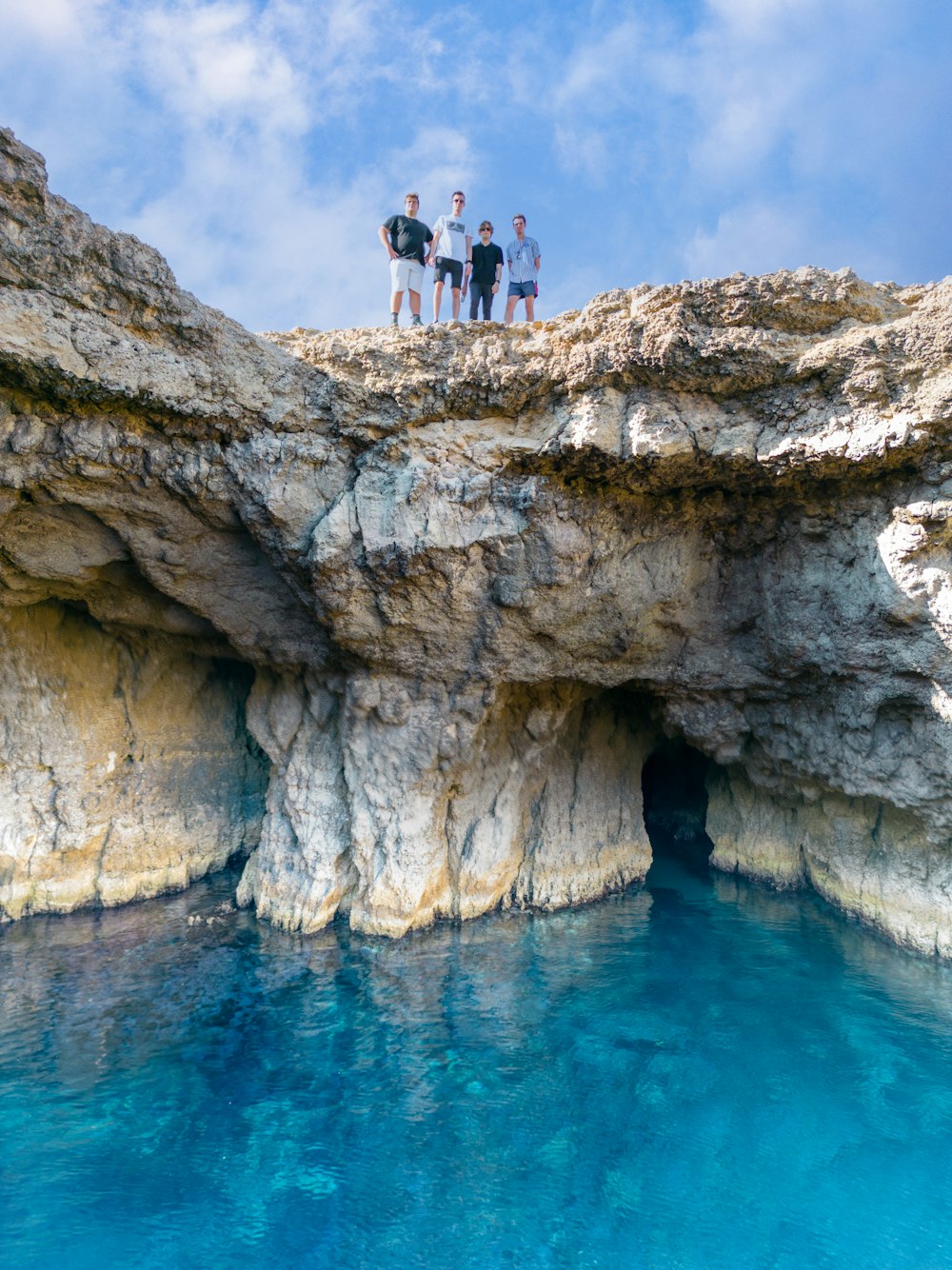 a group of people standing on a cliff above water