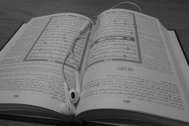 Elegant black and gold themed photo of a person reading the Mente Milionária book with audiobook headphones nearby.