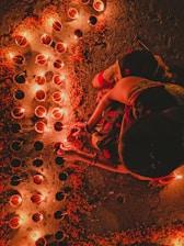 A serene morning scene with a person lighting a diya (oil lamp) beside a small altar adorned with flowers and sacred idols.
