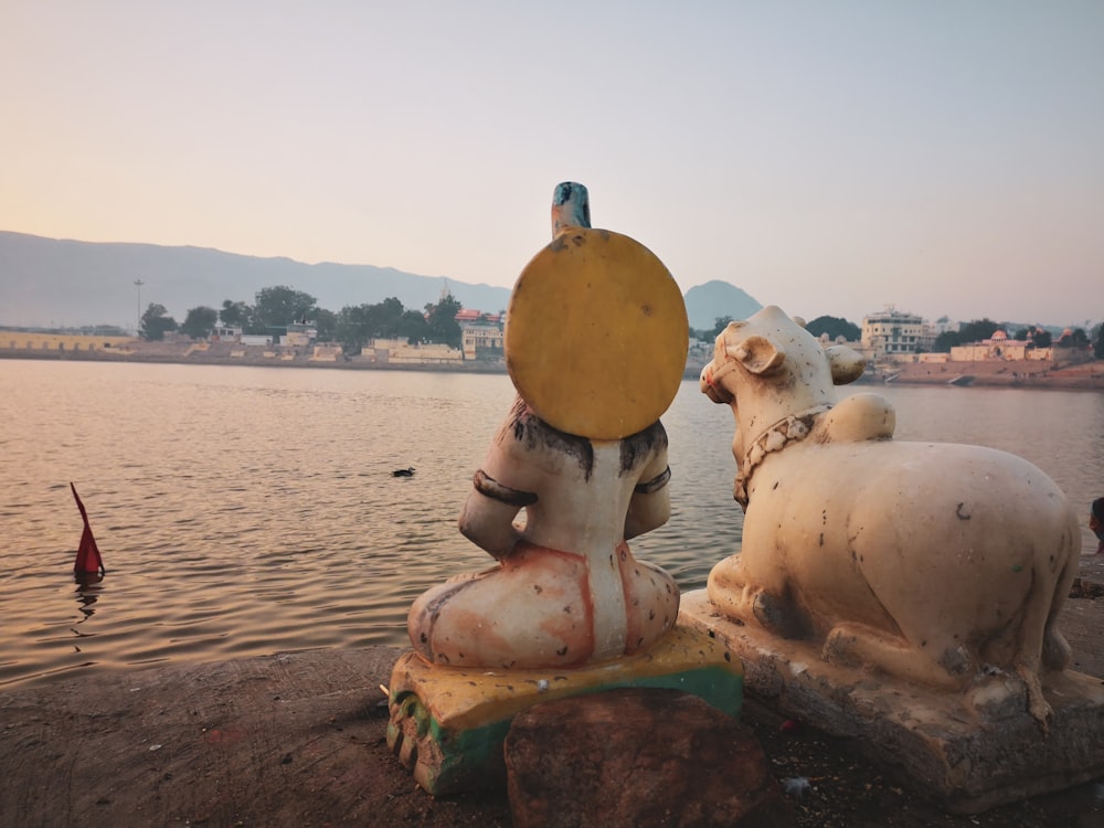 a couple of statues by a body of water