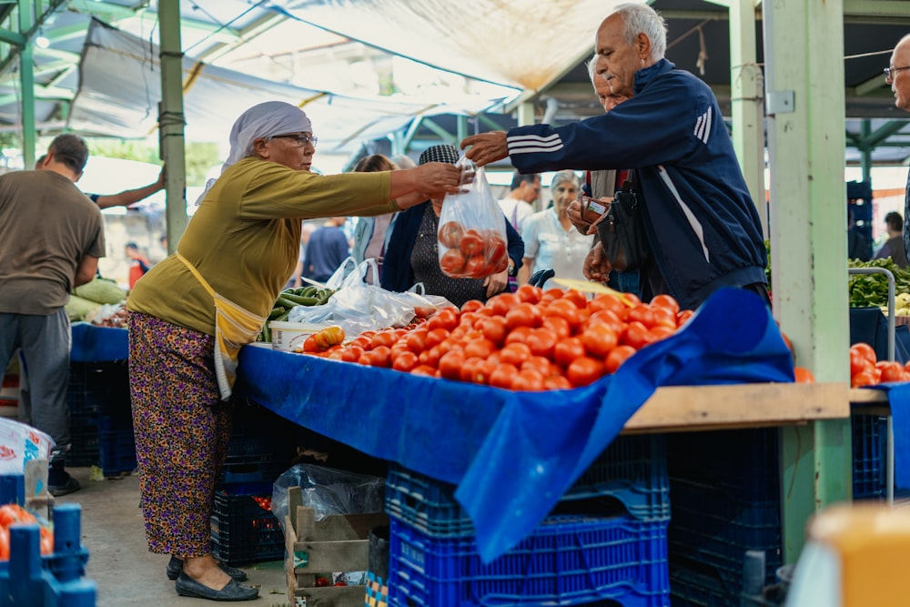 a man and woman buying fruits at a farmers market
