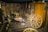 The room is filled with antique wooden tools and wagon wheels, displayed against wooden walls and floors. Various woodworking tools hang on the walls, creating a rustic and historical atmosphere similar to an old blacksmith or craftsman shop.