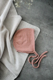 Handmade infant dresses and rompers displayed on soft gray fabric background.