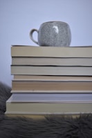 Cozy coffee mug beside a stack of business books and a tablet displaying notes