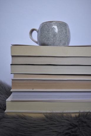 Close-up of a warm white ceramic mug resting on a taupe linen cloth beside a stack of home décor books.