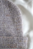 A cozy crochet hat in muted tones resting on a wooden table.