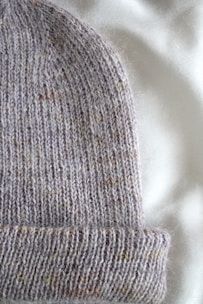 Close-up of a soft corduroy cap in warm autumn tones resting on a wooden table.