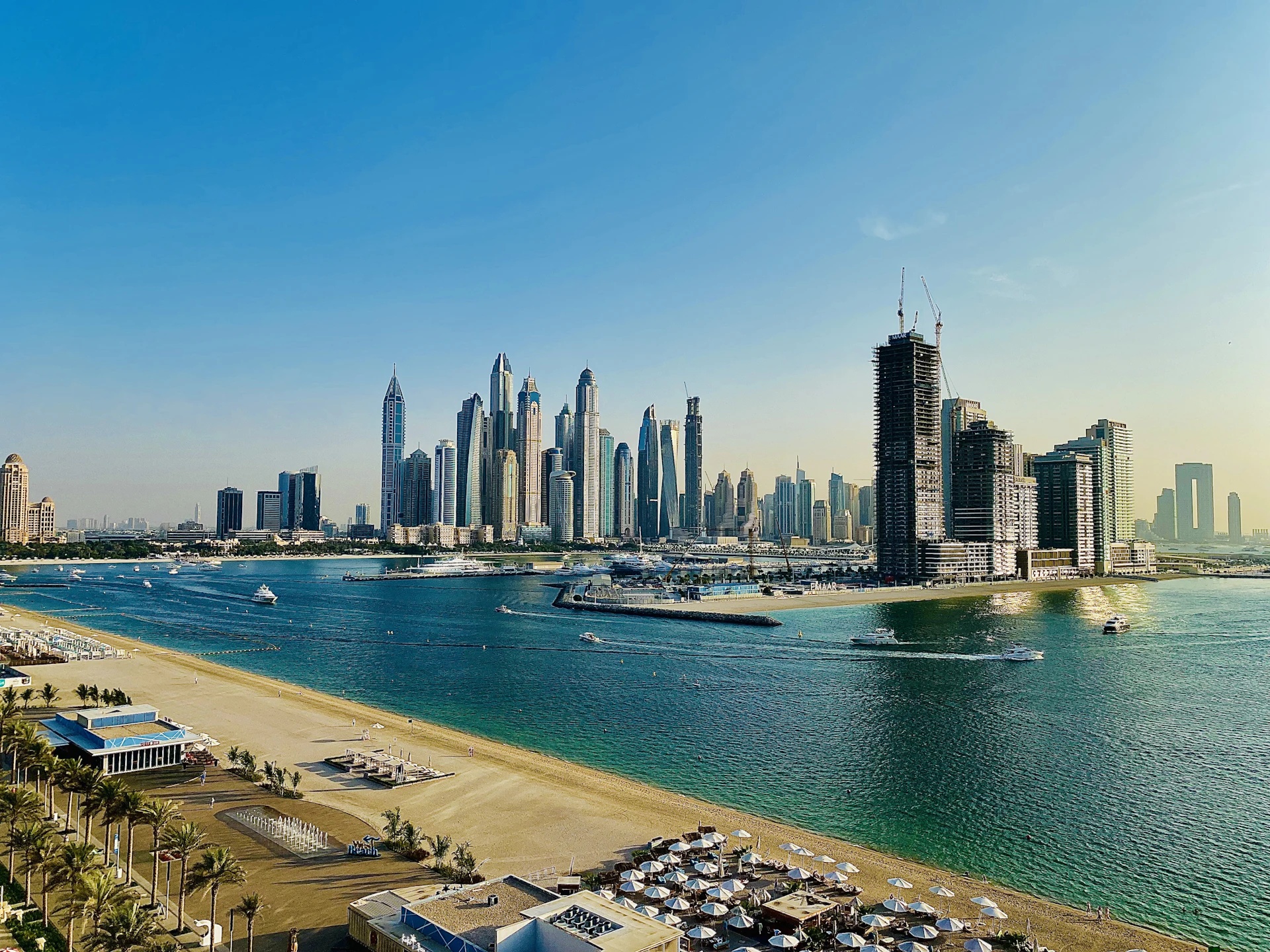Dubai city skyline rising behind a sandy beach and turquoise water