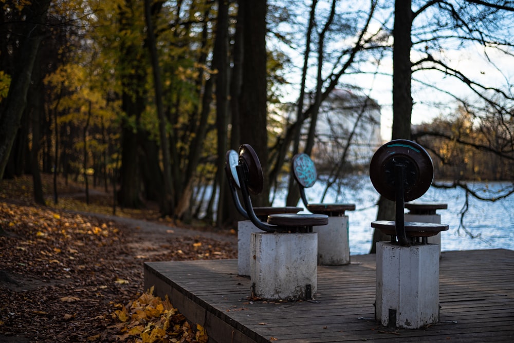 a wooden platform with a metal object on it by trees and a body of water