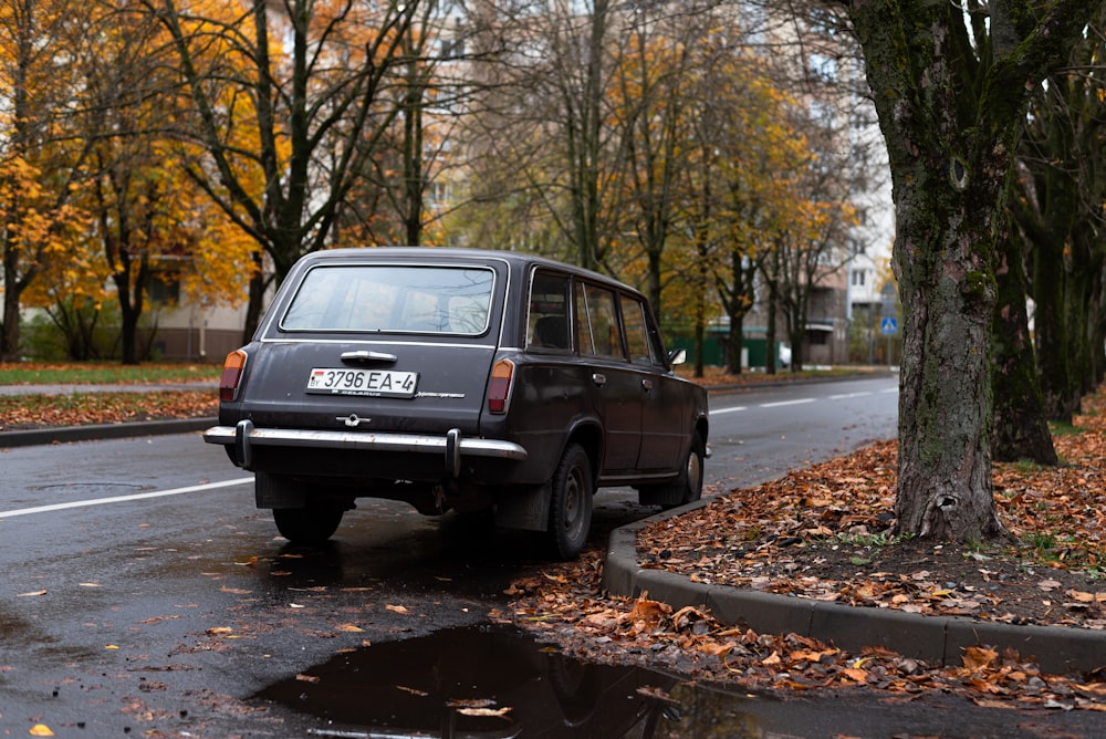 a car parked on the side of a road with trees on the side