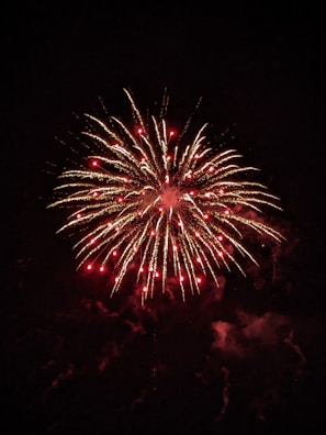 A smoky night scene illuminated by a massive golden firework bloom with subtle green highlights.