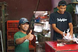 Friendly butcher handing a wrapped meat package to a smiling customer inside the shop.