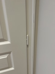 Picture of a handyman fixing a door hinge in a home.