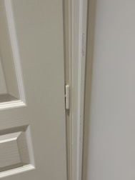 A locksmith repairing a damaged door hinge with tools.