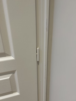 Close-up of a technician fixing a door hinge with tools on a sunny day.