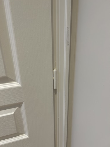 Close-up of durable metal door hinges with a brushed finish on a wooden door frame.