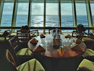 a table with glasses and bottles on it by a window with water