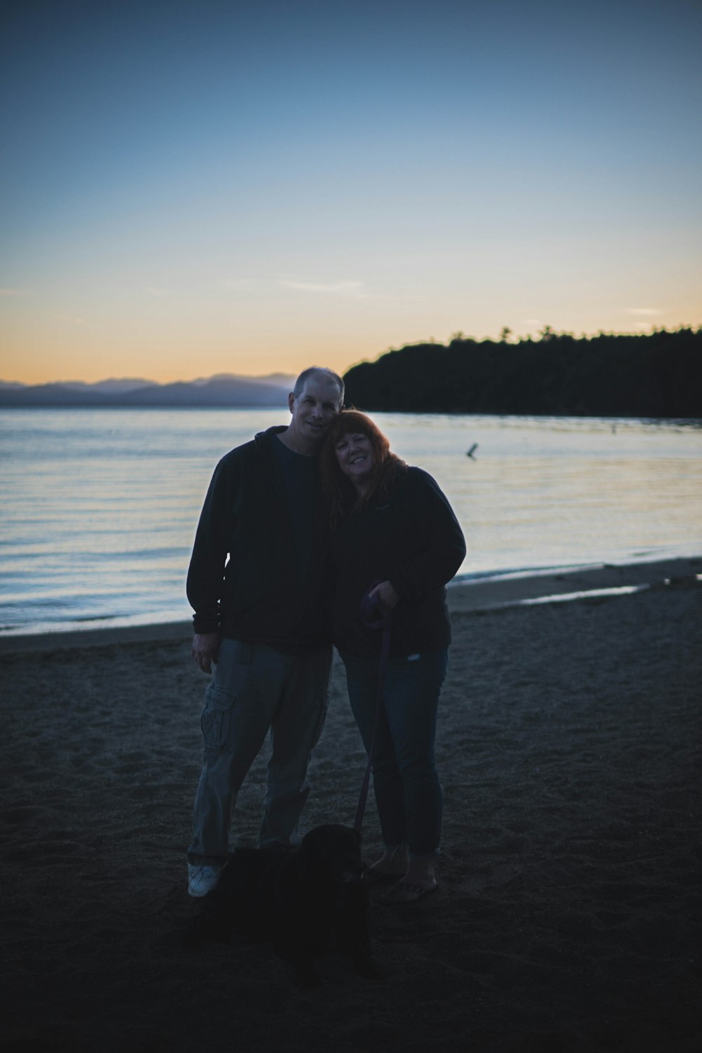 um homem e uma mulher posando para uma foto em uma praia