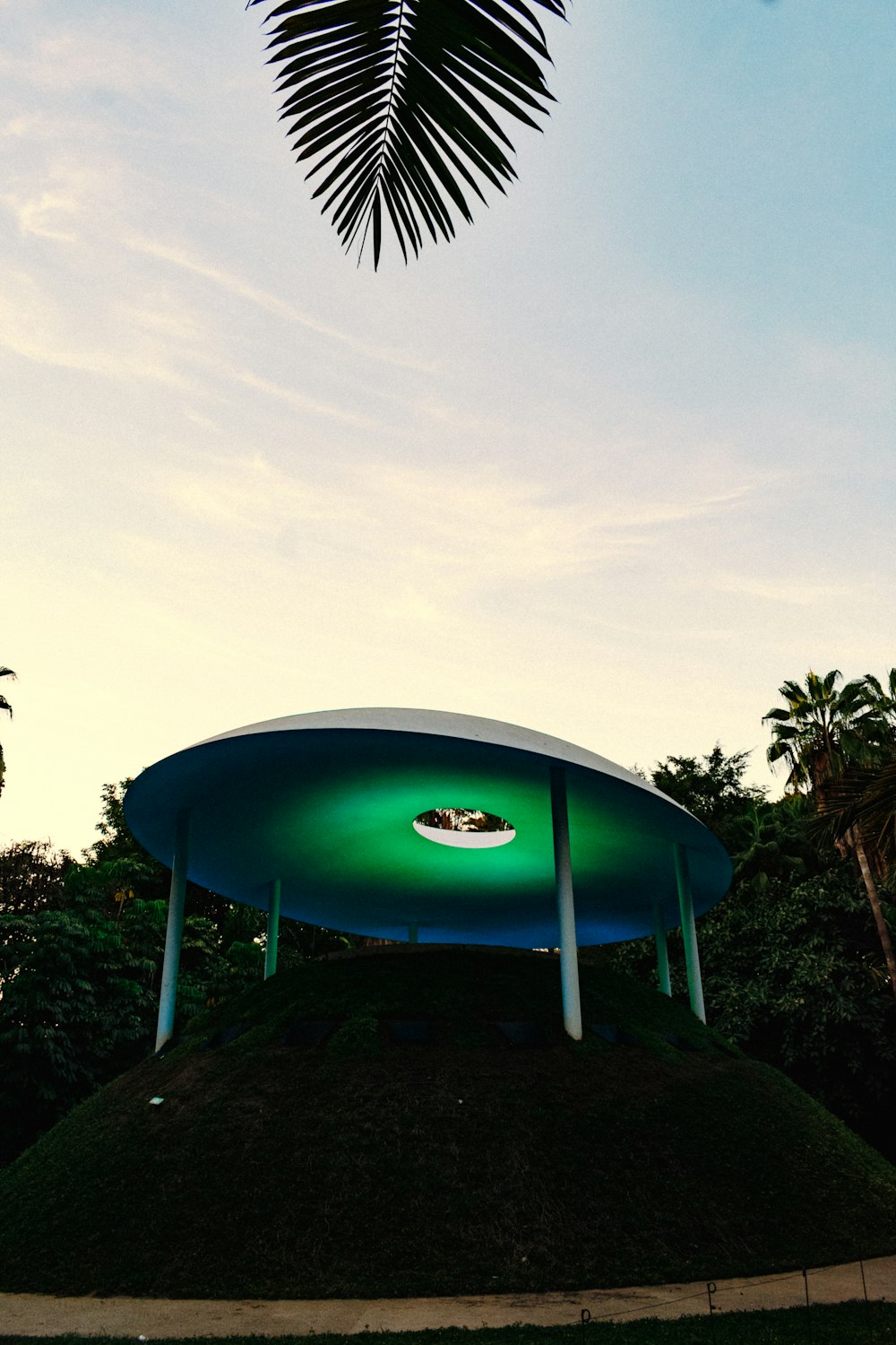 a blue trampoline with trees and a blue sky