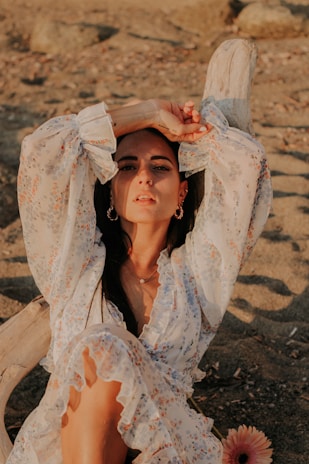 A close-up of a flowy skirt with floral patterns, resting on a sandy beach.