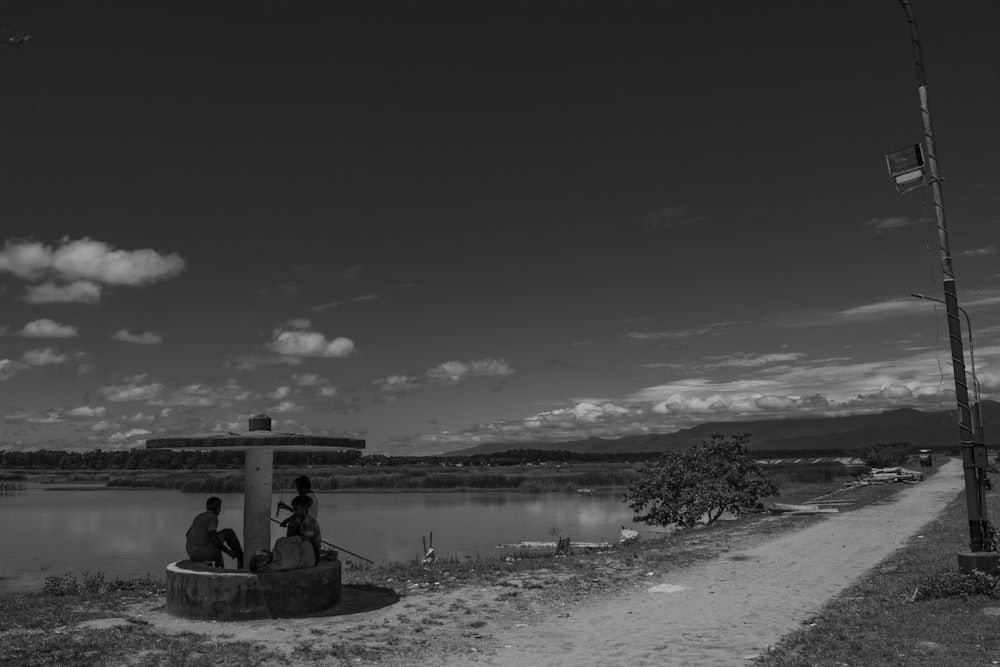 a black and white photo of a lake with a couple of people sitting on a bench