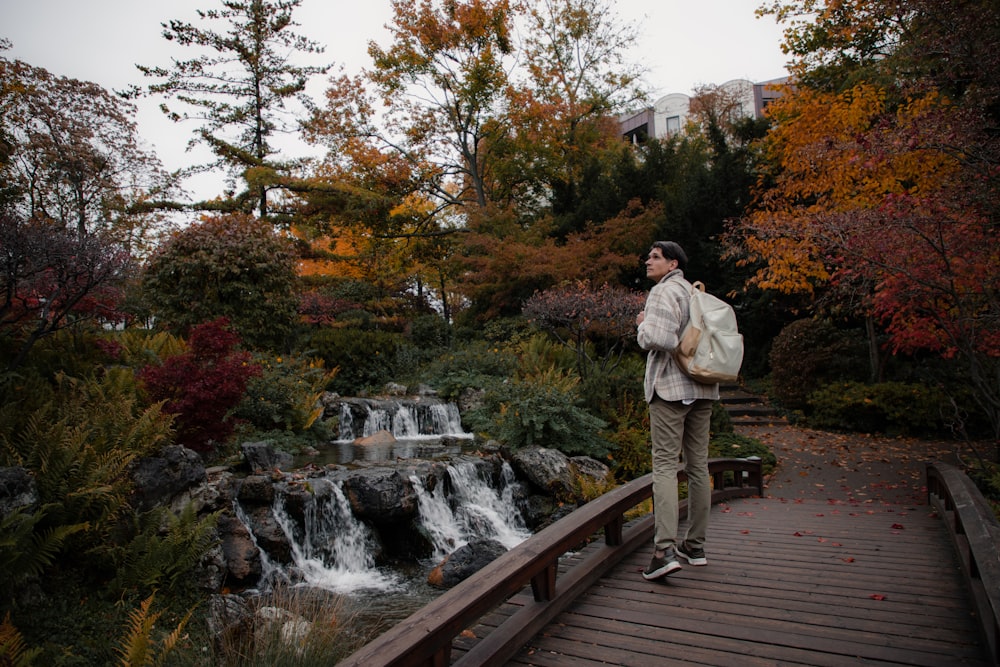 a man standing on a bridge over a river with trees and buildings