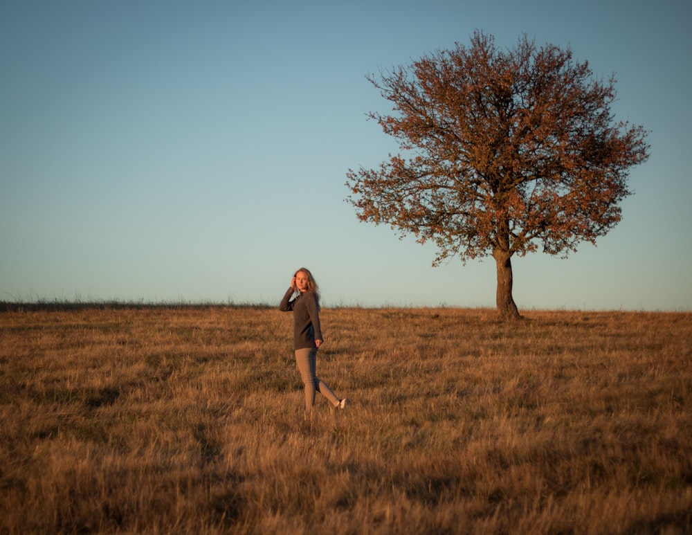Ein Mann steht auf einem Feld mit einem Baum im Hintergrund