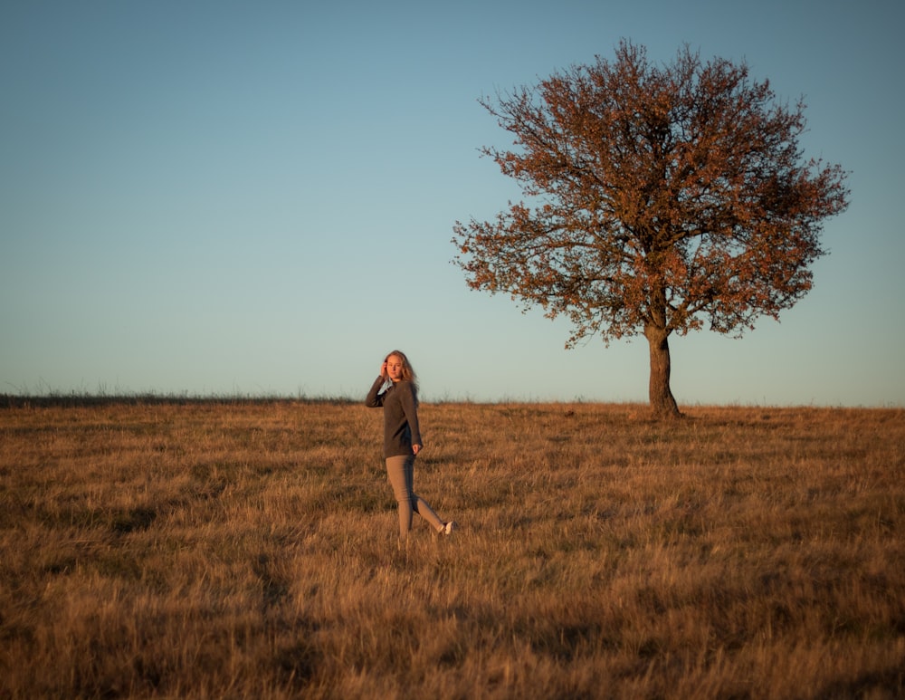 a man standing in a field with a tree in the background