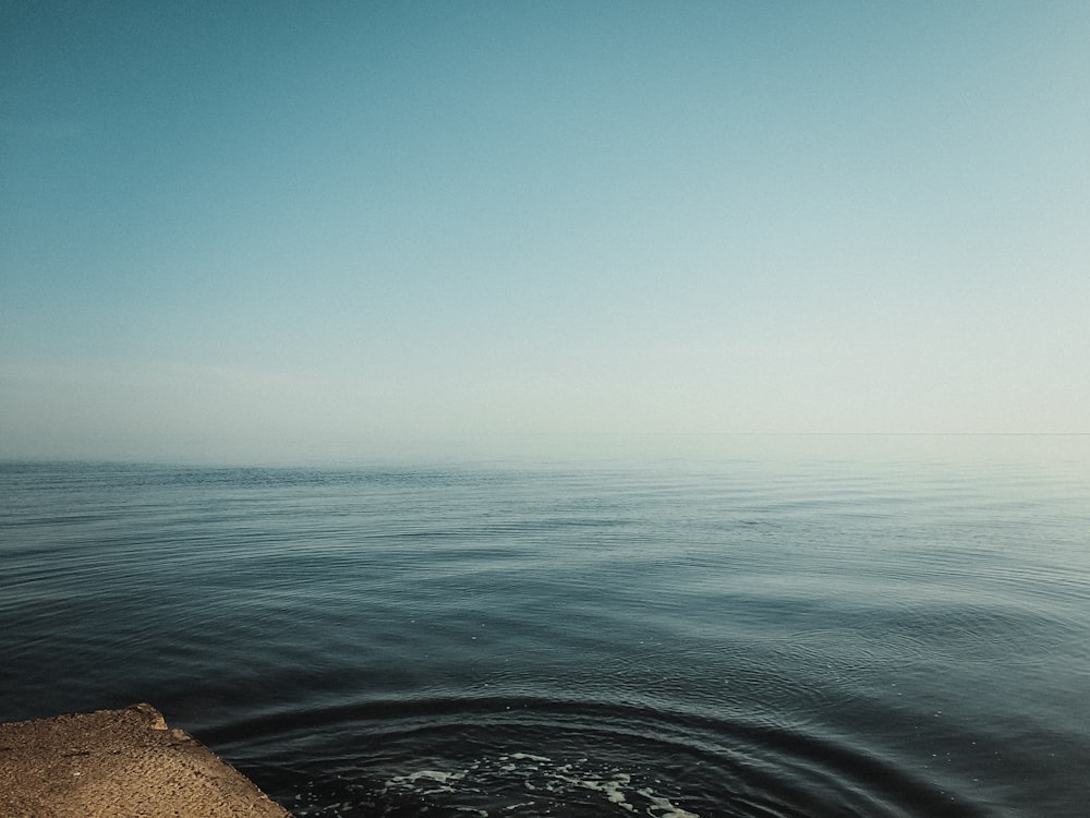 a body of water with a sandy beach and blue sky