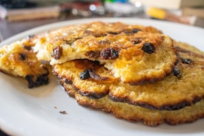A close-up of fluffy pancakes dusted with kinako powder and drizzled with honey on a rustic wooden plate.