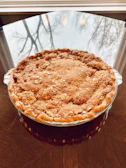 Freshly baked sweet potato pie cooling on a windowsill with sunlight streaming in.