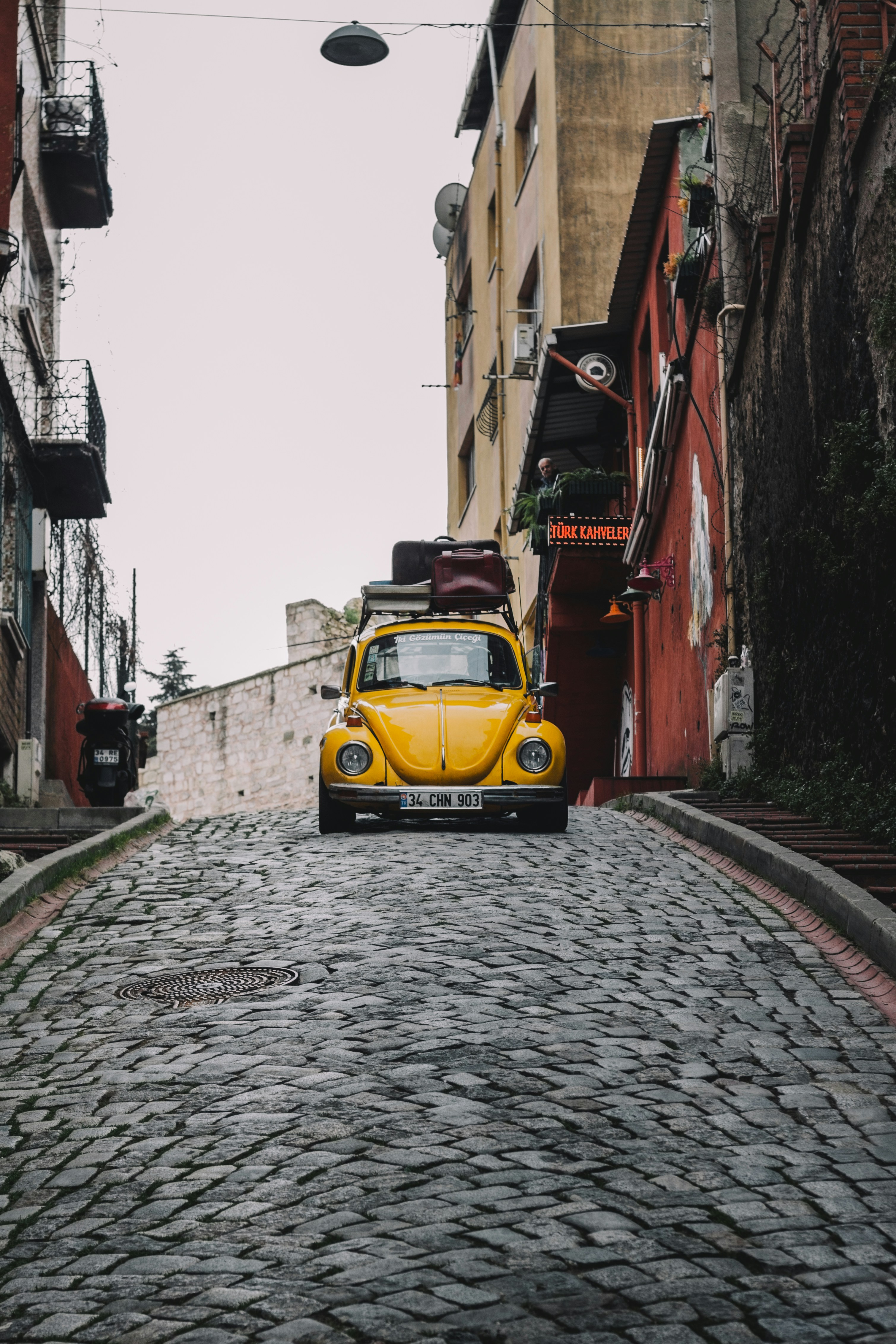 a yellow truck parked in a narrow street between buildings