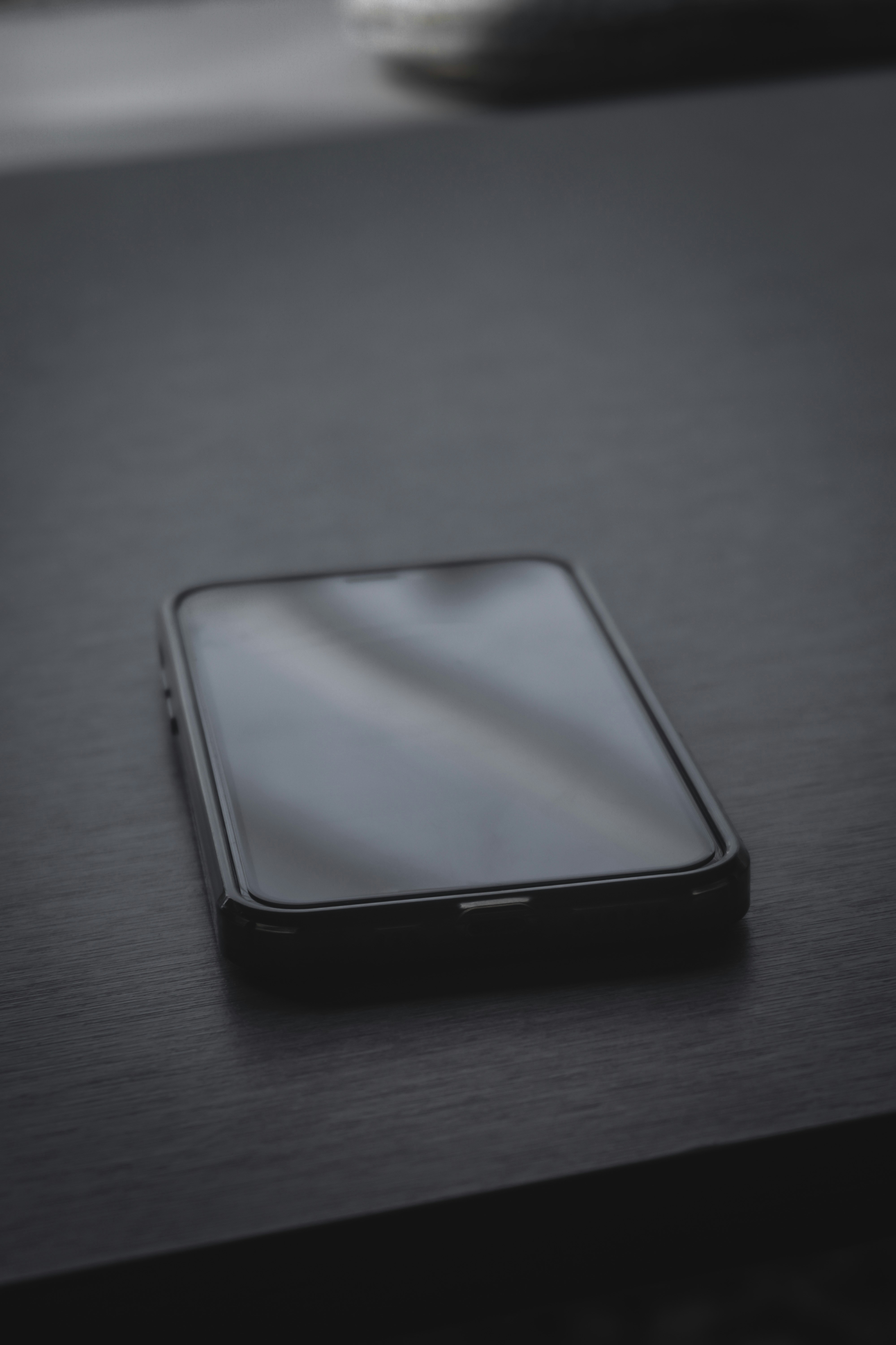 Выключенный смартфон на тёмной поверхности