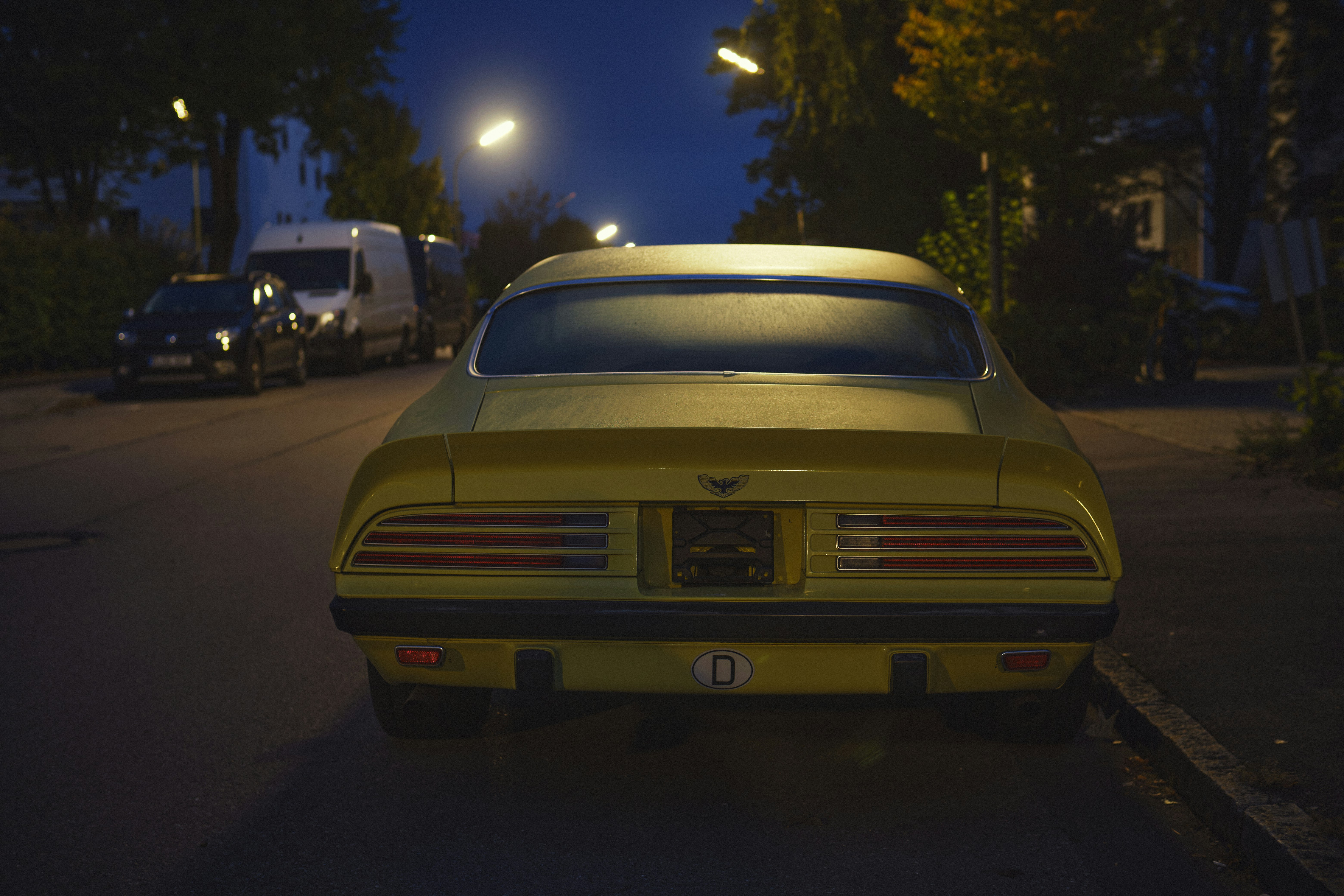 um carro esportivo amarelo estacionado ao lado de uma rua à noite