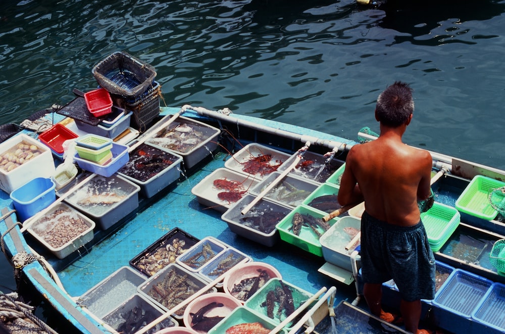 a man standing next to a boat full of fish