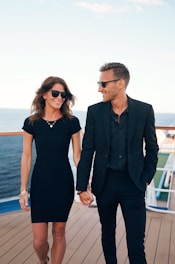 a man and woman wearing sunglasses and standing on a deck