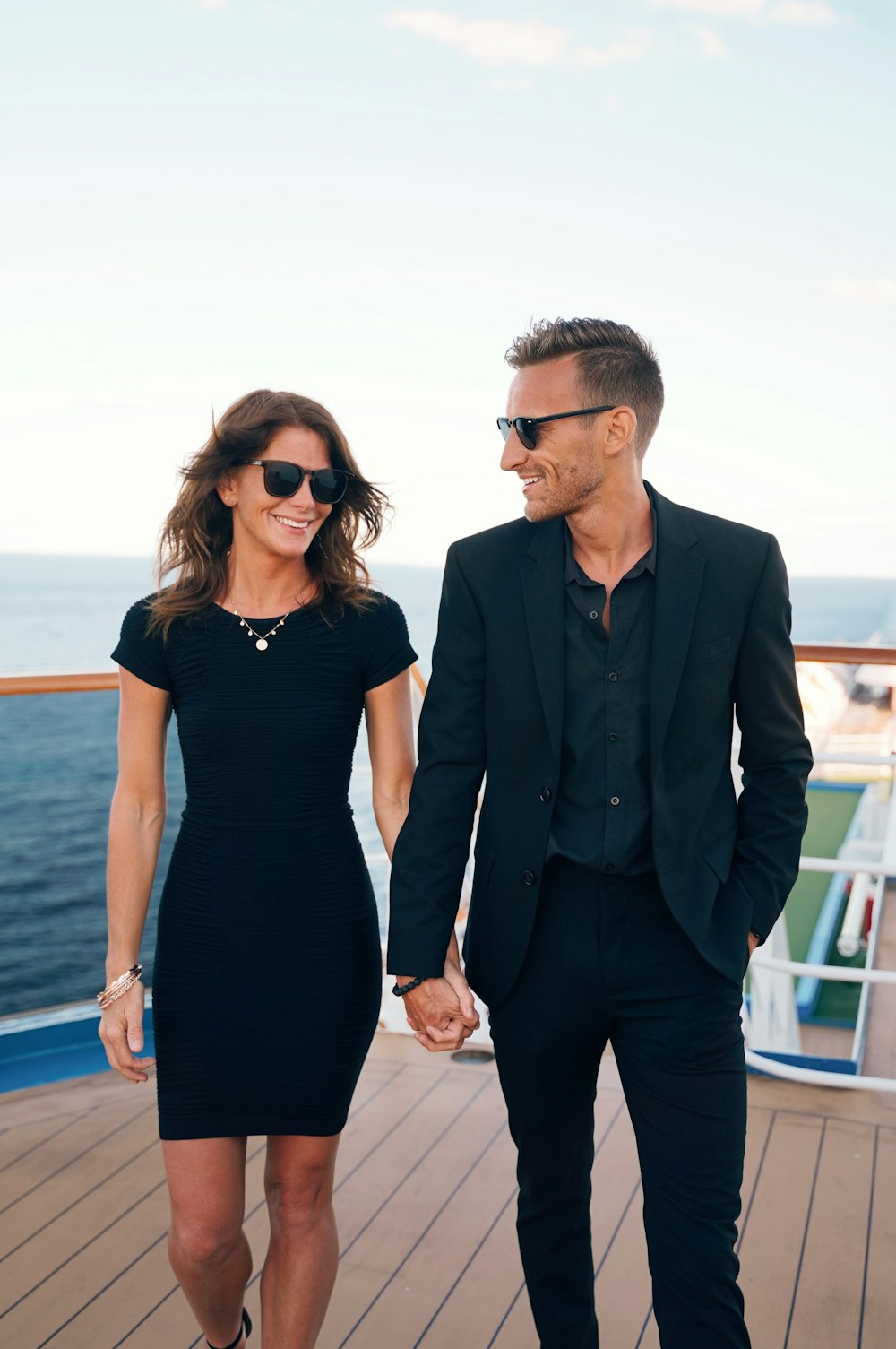 Un uomo e una donna che indossano occhiali da sole e in piedi su un ponte