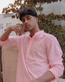 A young person wearing a breathable Roze Pulse tee, leaning against a sunlit wall on a quiet Bengaluru street.