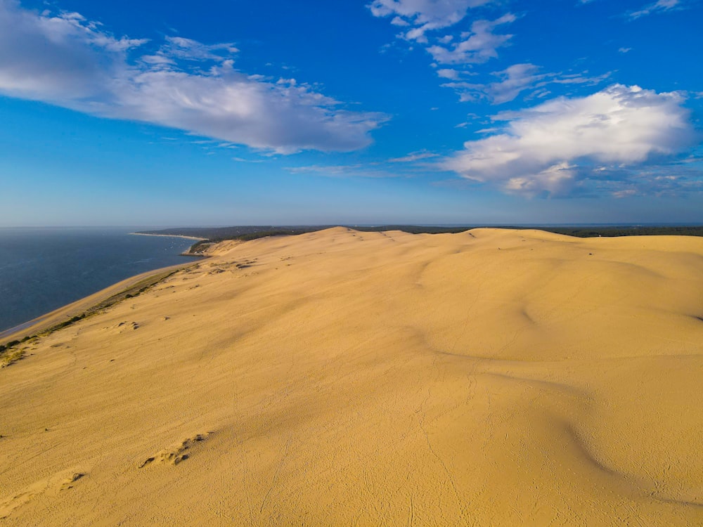 a sandy beach with blue sky and clouds