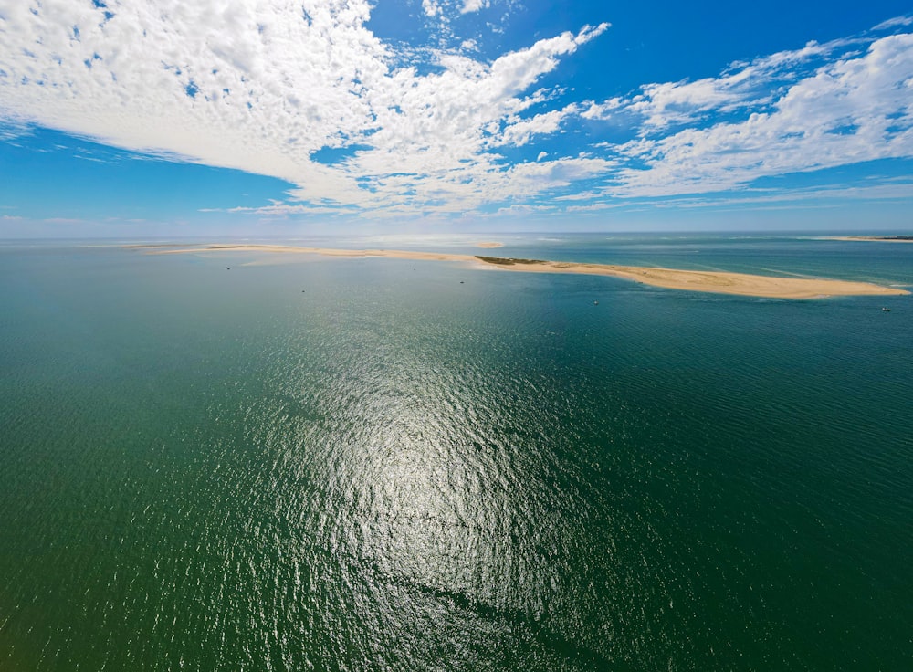 a body of water with a beach and clouds in the sky