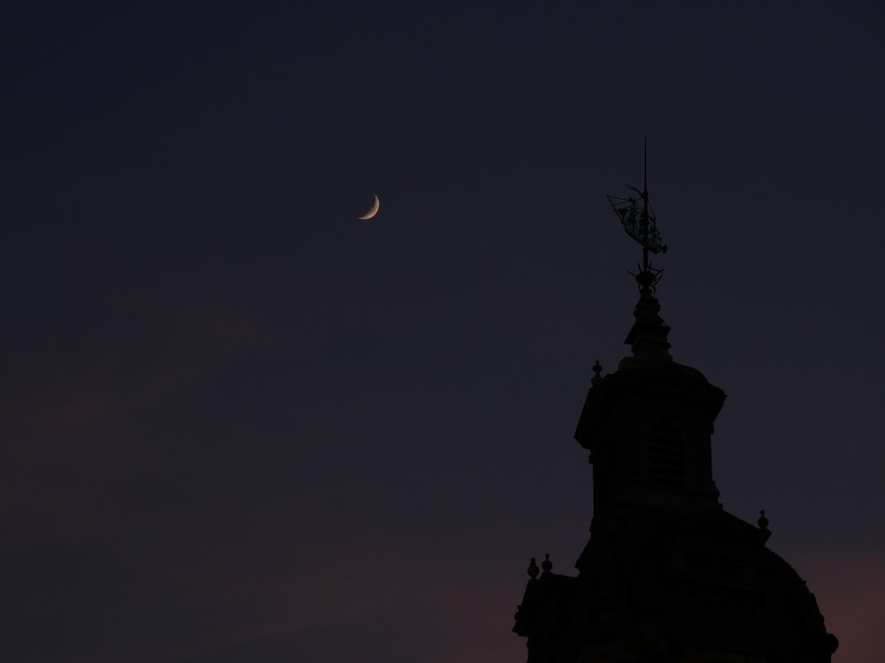 a silhouette of a building and a moon in the sky