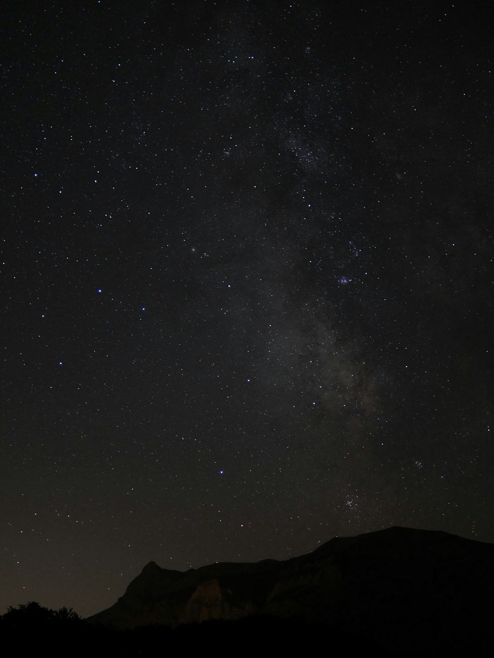 a starry night sky over a mountain range