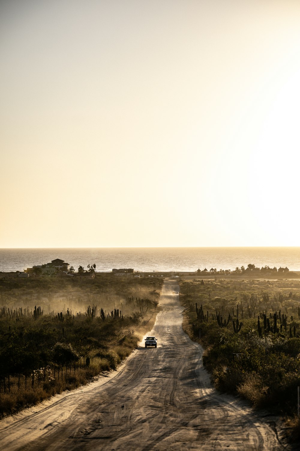 a dirt road with a car on it by a beach